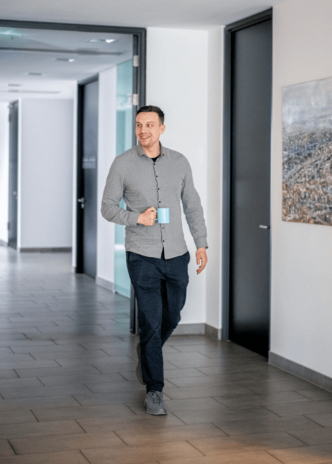 Auszubildender mit Tasse in Hand durch Flur gehend
