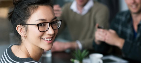 Junge Frau mit Brille lächelt in Kamera