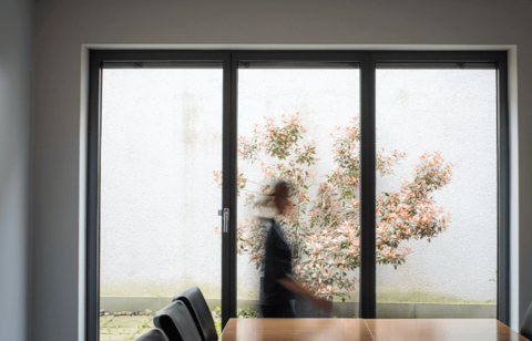 Person läuft vor einem Fenster im Besprechungsraum verschwommen am Betrachter vorbei